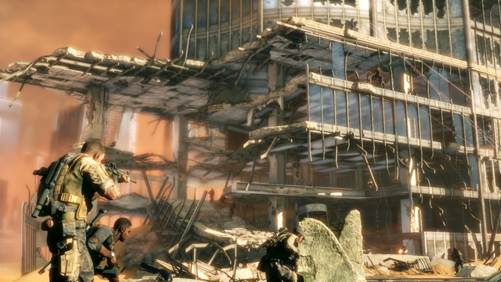 Eine Szene dem Videospiel Spec Ops: The Line. Eine Gruppe männlicher Soldaten steht in einem Wüstengebiet vor einem zerstörten Hochhaus mit Glasfassade.